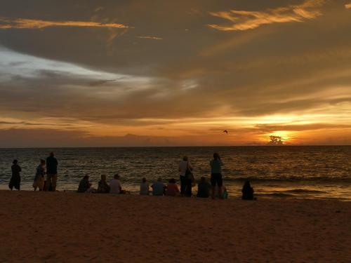 a group of people sitting on the beach at sunset at Marari SeaLap Beach Villas in Mararikulam