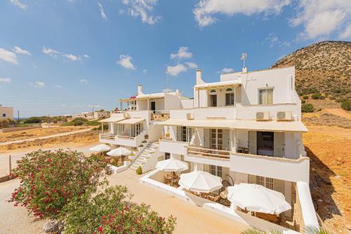 une grande maison blanche avec des parasols dans le désert dans l'établissement Studios Strouvalis, à Agiassos