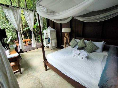 a bedroom with a bed with white sheets and pillows at Proud Phu Fah Maerim Resort in Mae Rim