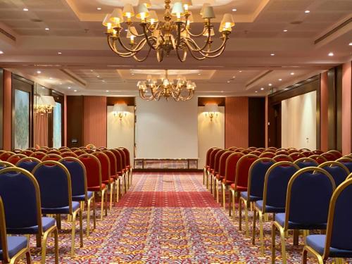 a conference room with red chairs and a chandelier at Royal Hotel Oran - MGallery Collection in Oran