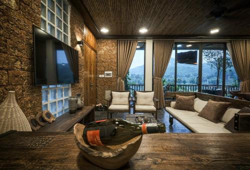a living room with a bottle of wine on a table at MyBinsu Villa - Venue Travel in Ba Vì