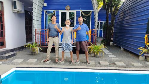 three people standing in front of a house with a pool at Airport Residence Inn in Katunayake
