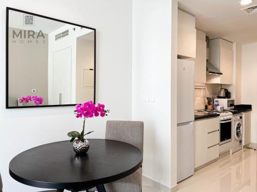 a dining room table with a vase of flowers on it at Mira Holiday Homes - Newly serviced apartment in Dubai South in Dubai