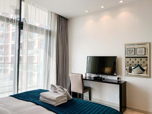 a hotel room with a bed and a desk and a television at Mira Holiday Homes - Newly serviced apartment in Dubai South in Dubai