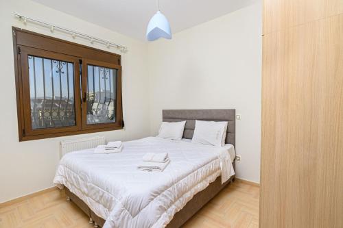 um quarto com uma cama com lençóis brancos e uma janela em 4 Seasons Home em Alexandroupoli