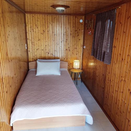 Cama pequeña en habitación con paredes de madera en VILLA KATERINA, en Tríkala
