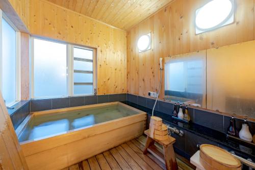 ein Bad mit einer großen Badewanne in einem Zimmer mit einem WC in der Unterkunft スイートヴィラ 那須高原カシェット in Nasu