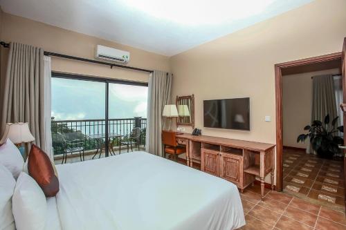 a bedroom with a bed and a television and a balcony at Venus Hotel Tam Đảo in Tam Ðảo