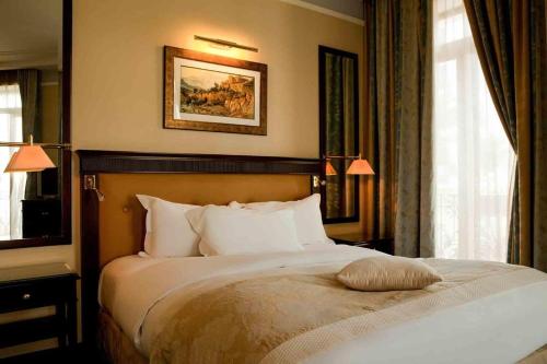 a bedroom with a large bed with two windows at Royal Hotel Oran - MGallery Collection in Oran