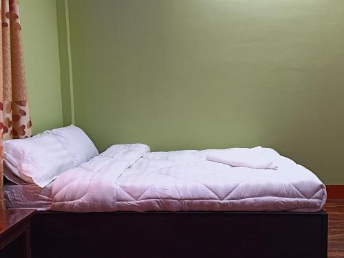 a bed with white sheets and pillows in a room at Dubochaur Rest house & homestay in Nagarkot