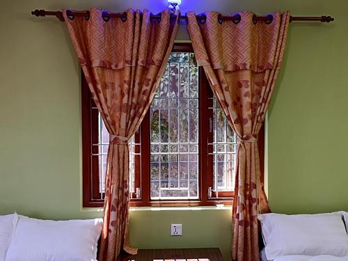 a bedroom with a window with curtains on it at Dubochaur Rest house & homestay in Nagarkot