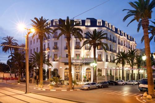 a large white building with palm trees in front of it at Royal Hotel Oran - MGallery Collection in Oran