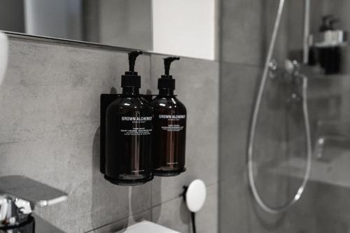 two bottles are hanging on a wall in a bathroom at The Place Herzogenaurach - Serviced Apartments in Herzogenaurach