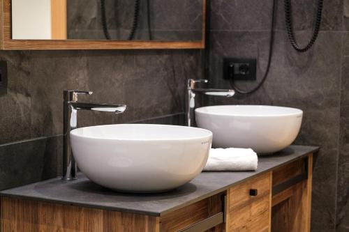 two sinks on a counter in a bathroom at La Dila Dolomiti Mountain Lodge in Andalo