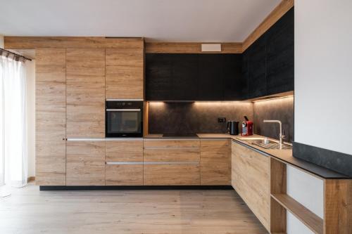 a kitchen with wooden cabinets and a microwave at La Dila Dolomiti Mountain Lodge in Andalo