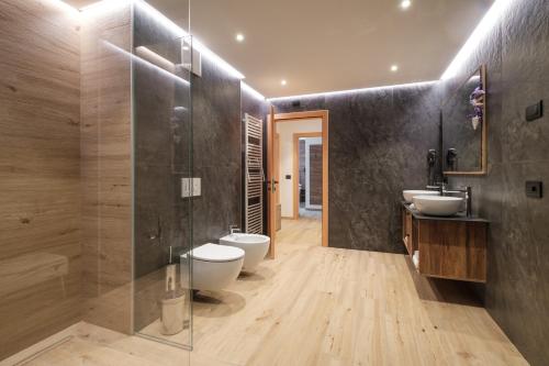 a bathroom with two sinks and a toilet and a shower at La Dila Dolomiti Mountain Lodge in Andalo