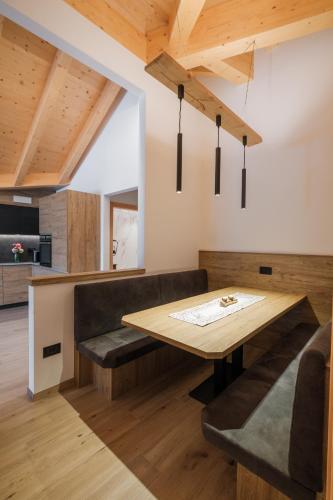a kitchen and dining room with a wooden table and benches at La Dila Dolomiti Mountain Lodge in Andalo