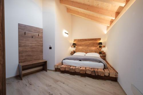 a bedroom with a large bed with a wooden headboard at La Dila Dolomiti Mountain Lodge in Andalo