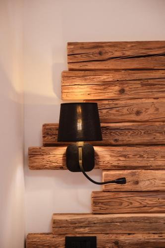 a lamp on the wall next to a stack of logs at La Dila Dolomiti Mountain Lodge in Andalo