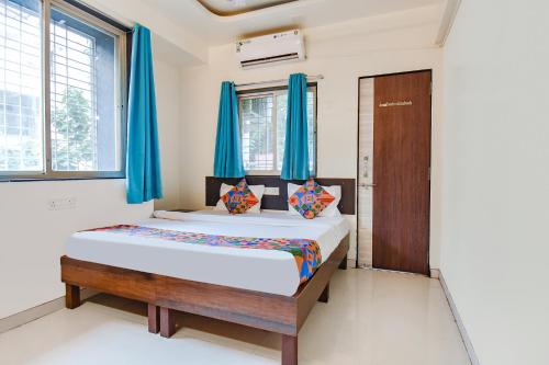 a bedroom with a bed with blue curtains and a door at FabExpress Galaxy Apartments - Lohegaon chowk in Pune