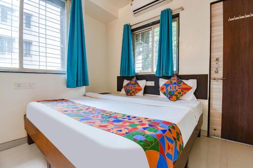 a bedroom with a bed with blue curtains at FabExpress Galaxy Apartments - Lohegaon chowk in Pune