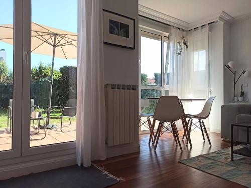sala de estar con mesa, sillas y puerta abierta en Bajo con jardín privado, en Santander