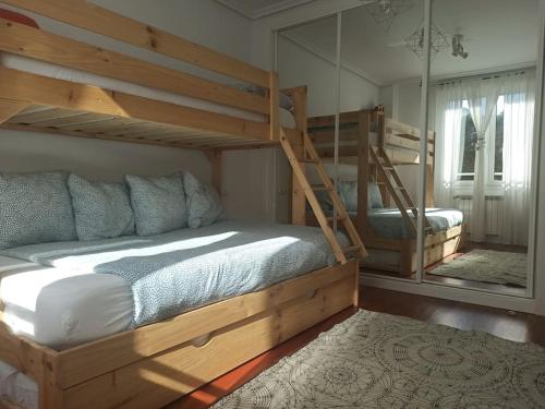 a bedroom with two bunk beds and a mirror at Bajo con jardín privado in Santander