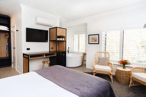 1 dormitorio con cama, bañera y TV en Chimes Spa Retreat, en Denmark