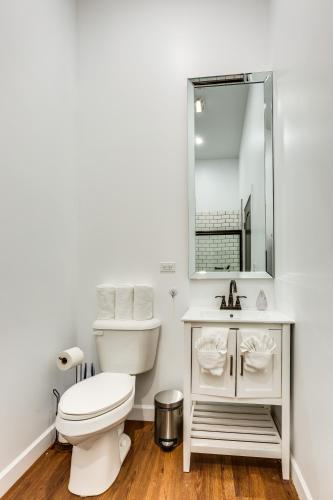 a bathroom with a toilet and a sink and a mirror at Converted Store Front Home Lets You Live Like a Local in the Heart of it All! condo in Chicago