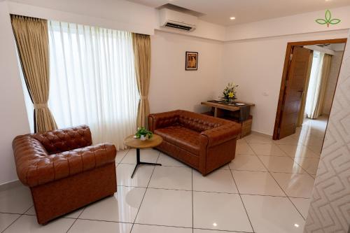 a living room with two leather chairs and a table at Tea Tree Suites,Manipal in Manipala