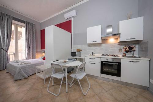 uma cozinha com armários brancos e uma mesa e cadeiras em Cattedrale Duomo 77 Apartments By Dimorra em Nápoles