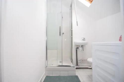 een witte badkamer met een douche en een wastafel bij 10mn RER B Aéroport CDG - Paris Gare du Nord, T11 Express, Le Bourget, Tout équipé, Netflix Gratuit, 3 personnes, 4ème étage, escaliers, Parc des Expositions, Parking rue Gratuit après 19h in Drancy