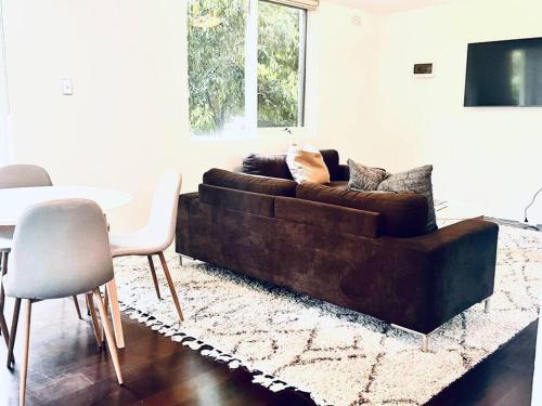 een woonkamer met een bruine bank en een tafel bij Two bedroom South Melbourne Apartment on Montague in Melbourne