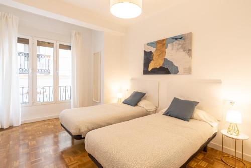 Habitación con 2 camas, paredes blancas y suelo de madera. en LUANDCIA Soho 3, en Málaga