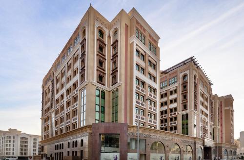 a large building with a tower on top of it at La Maison Hotel Doha in Doha