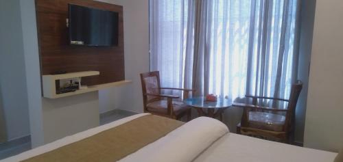 a bedroom with a bed and a table with chairs at Hotel Success Residency in Ghansoli
