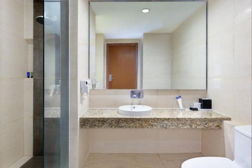 a bathroom with a sink and a mirror at ASTON Jember Hotel & Conference Center in Jember