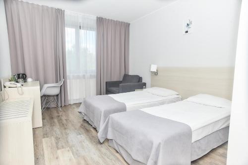 une chambre d'hôtel avec deux lits et une chaise dans l'établissement Hotel Sphinx, à Żabia Wola