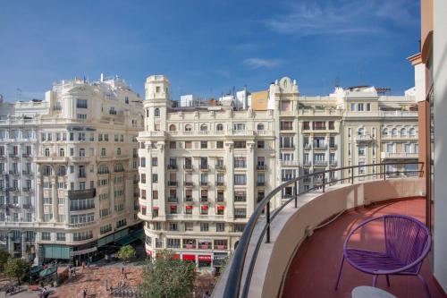 una silla púrpura en un balcón frente a los edificios en Casual Vintage Valencia en Valencia