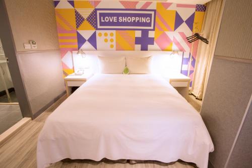 台北的住宿－西門星辰大飯店，一张大白色的床,位于一个有爱情购物标志的房间