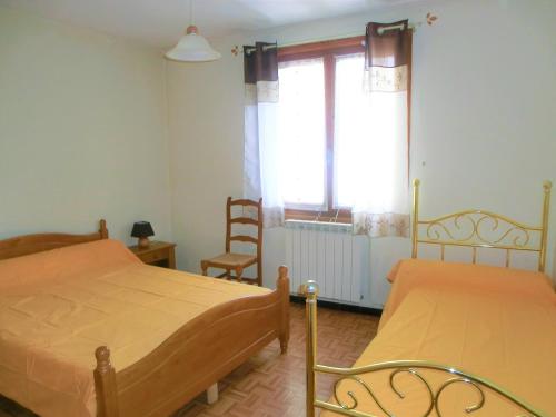 a bedroom with two beds and a window and a chair at LOU FILADOUR 6 personnes 1er étage in Jausiers