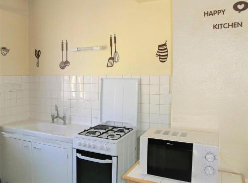 a small kitchen with a stove and a sink at LOU FILADOUR 6 personnes 1er étage in Jausiers