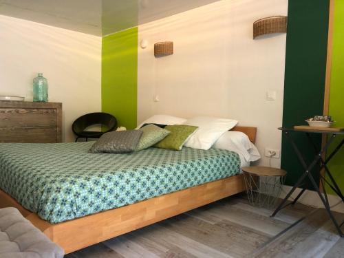 a bedroom with a bed with green and white walls at Le jardin de félicie in Trévoux