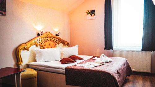 a hotel room with a bed with a wooden headboard at Vila Europa in Cluj-Napoca