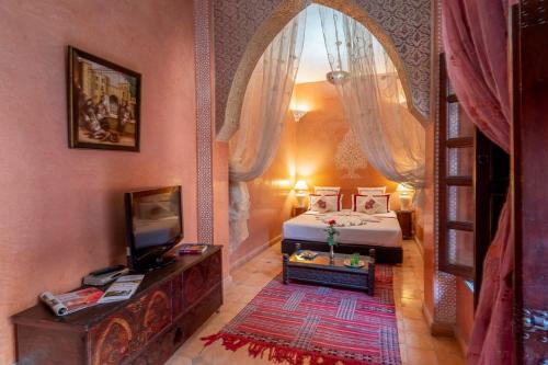 ein Schlafzimmer mit einem Bett und einem TV in einem Zimmer in der Unterkunft Riad Rêves D'orient & Spa in Marrakesch