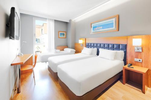 バルセロナにあるバルセロナ センチュリー ホテルのベッド2台とテレビが備わるホテルルームです。