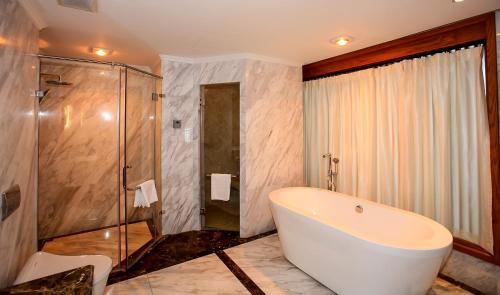 y baño con bañera y ducha acristalada. en Venus Hotel Tam Đảo, en Tam Ðảo