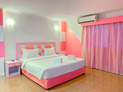 a pink and white bedroom with a large bed at The Wai Hotel Danok in Sadao