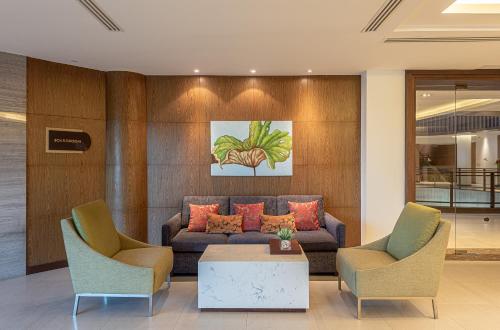 a living room with a couch and two chairs at Summit Windmill Golf Suite Hotel at Suvarnabhumi in Bangna