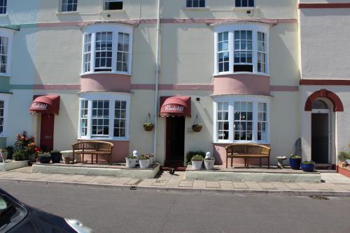 a pink and white building with benches in front of it at The Redcliff in Weymouth